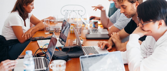 Colaboradores trabajando en equipo con laptops durante una capacitación empresarial de inglés.
